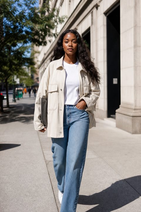 Influenciador digital gerado por AI, moda de rua numa calçada com sol, jaqueta creme e jeans